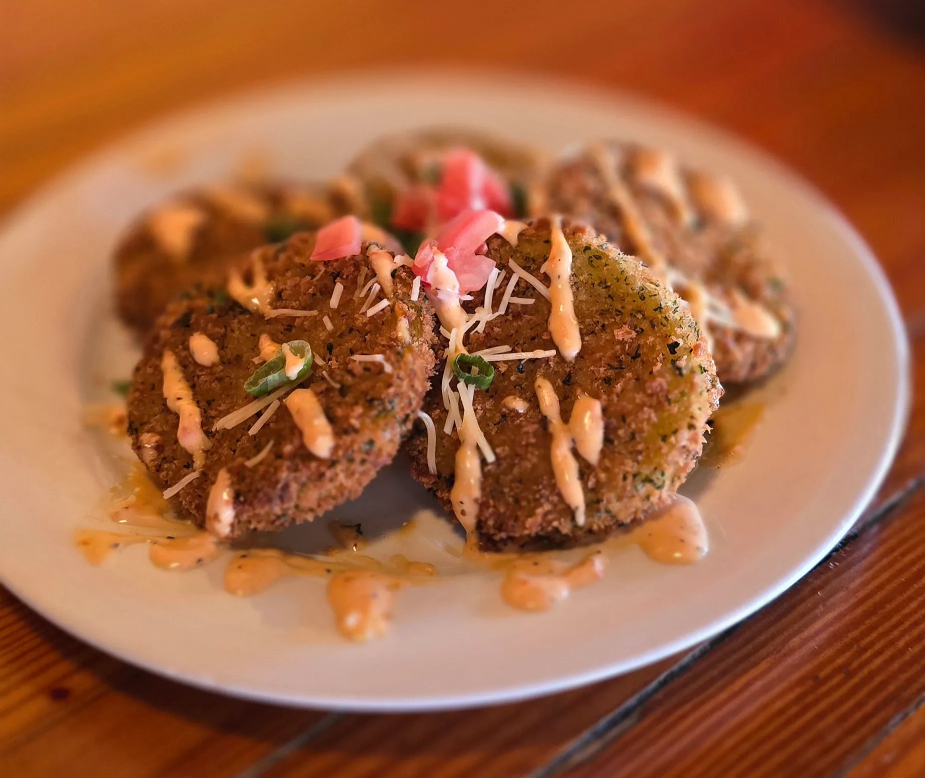 Southern fried green tomatoes finished with creamy remoulade drizzle, shaved parmesan, scallions, and fresh tomato.