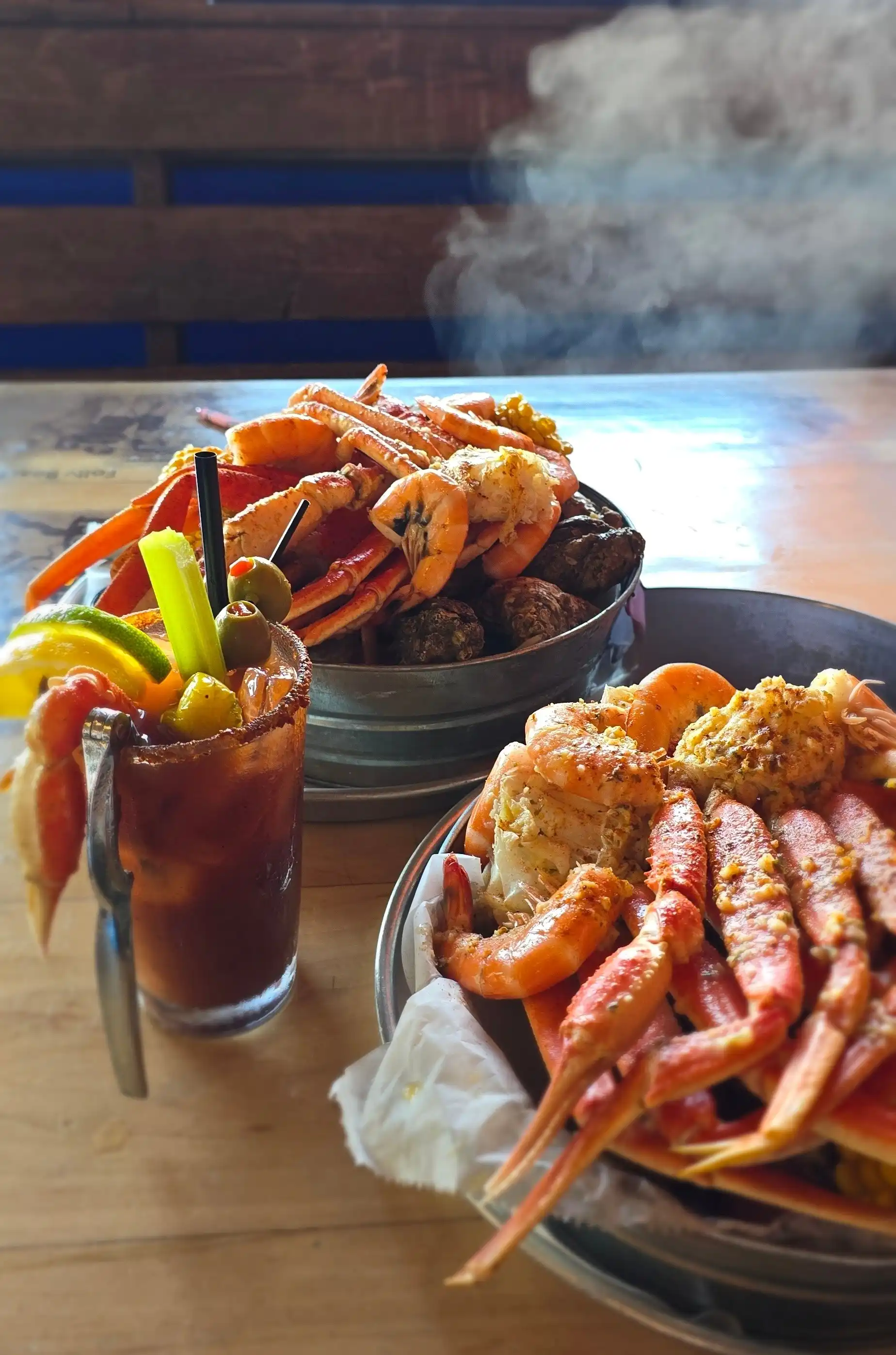 Two signature steamed seafood buckets — snow crab clusters, large shrimp, and oysters — paired with a fully loaded Crabby Mary Bloody Mary.