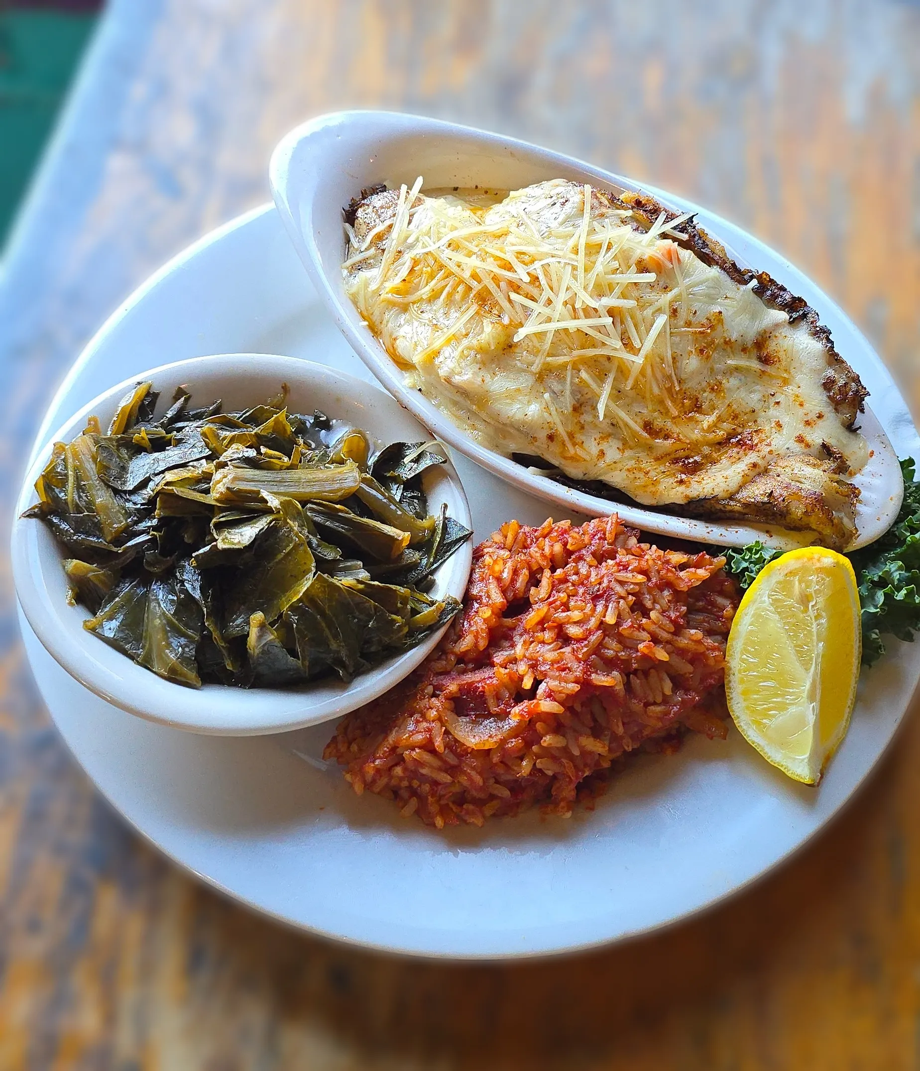 Crab Stuffed Flounder — seared flounder filled with blue crab and topped with sherry cream sauce, served with red rice, Lowcountry collard greens, and a fresh lemon wedge.