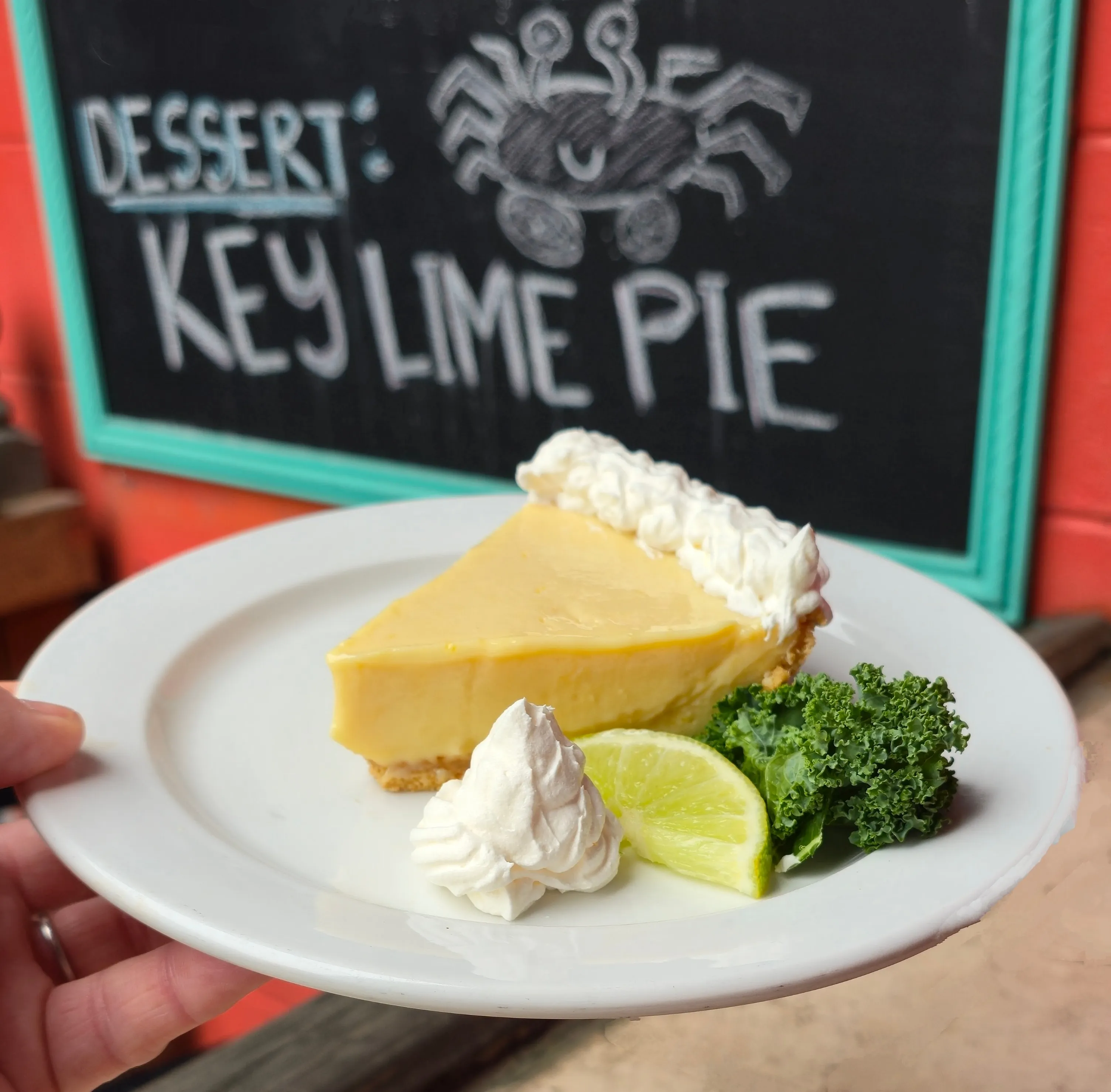 A creamy slice of Key Lime Pie crowned with whipped cream, garnished with a fresh lime wedge.