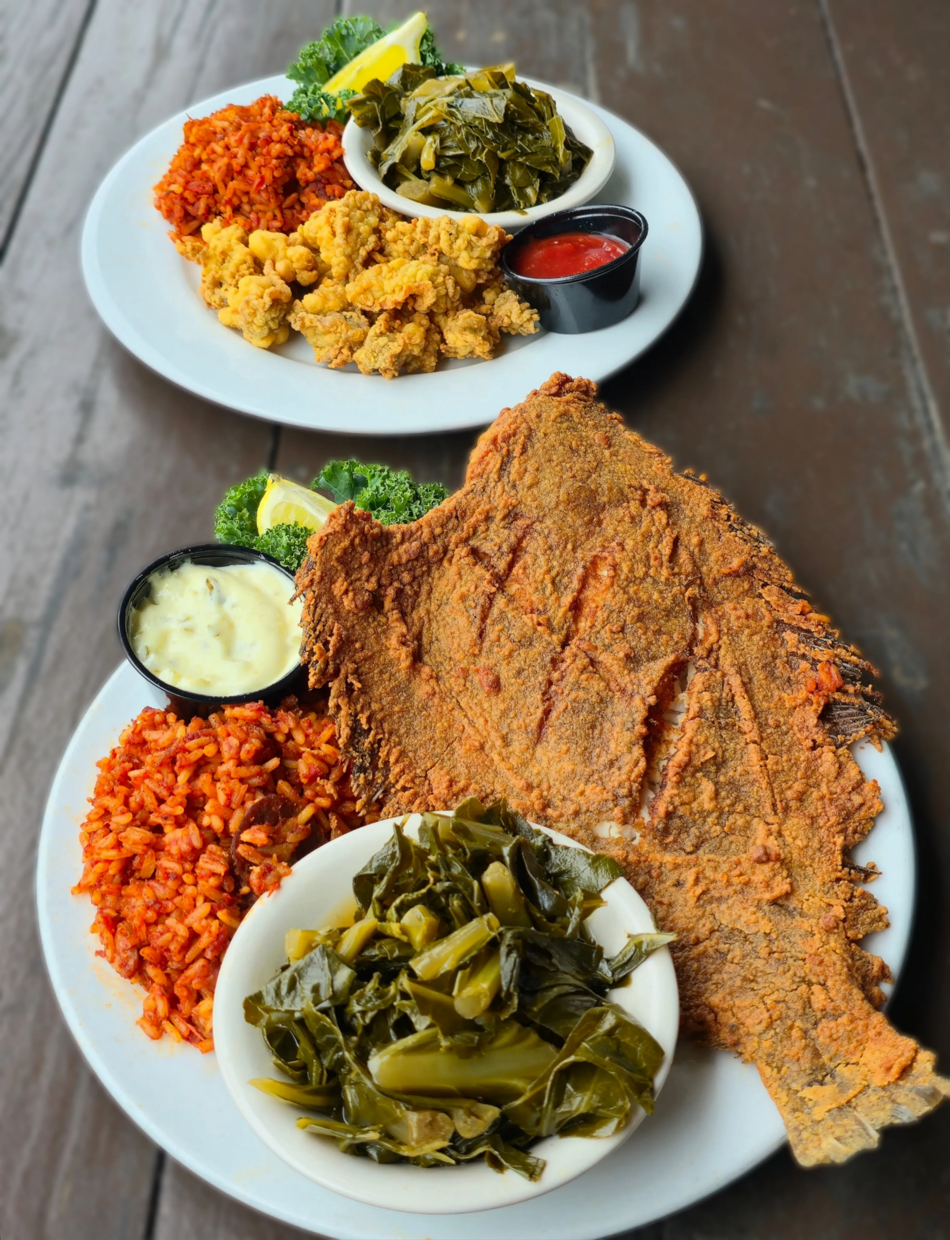 Two Shack classics — a plate of golden fried oysters with red rice and collards, and a whole crispy fried flounder served with red rice, collards, and tartar sauce.
