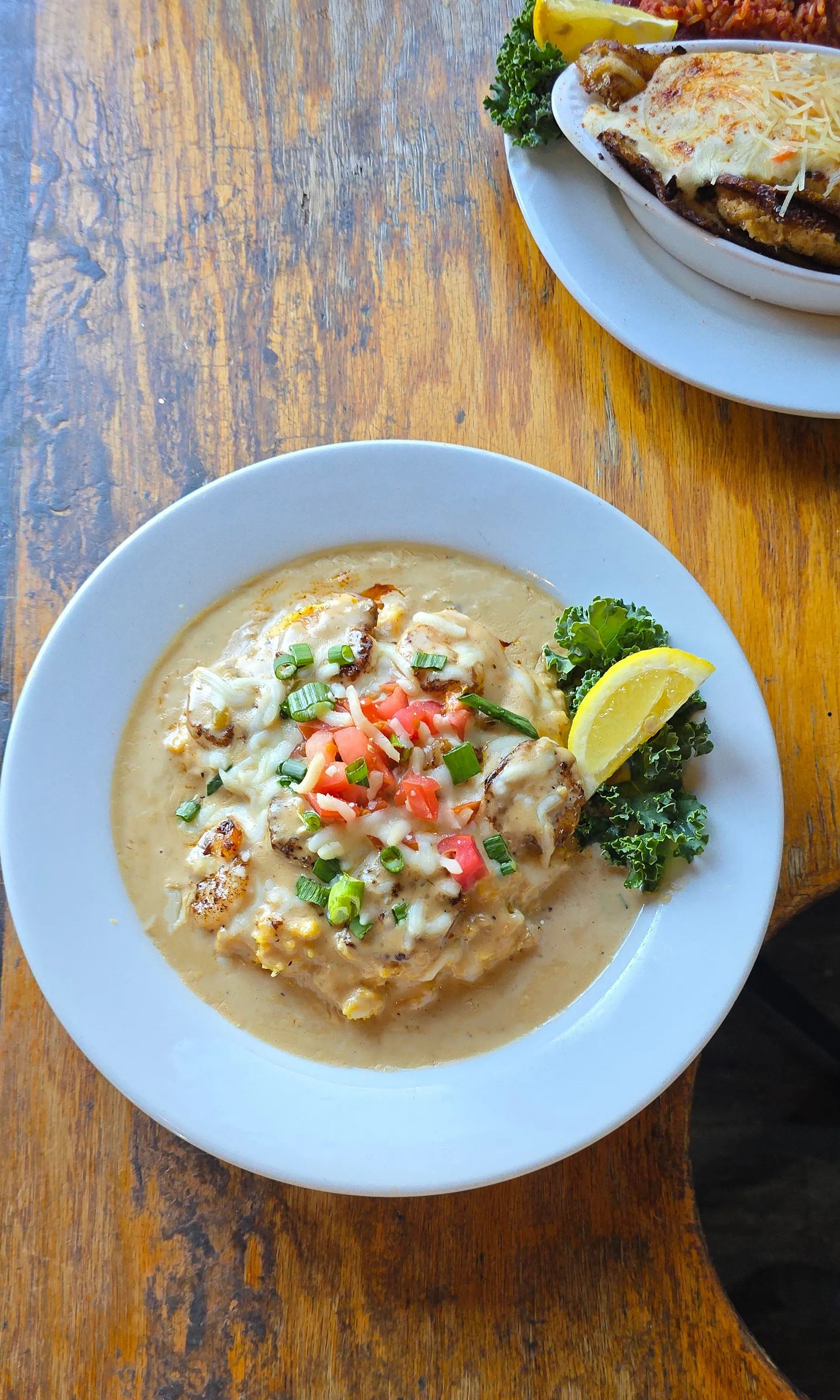 Lowcountry Shrimp & Grits — seared shrimp over stone-ground grits with Tasso gravy and cheeses, finished with scallions and diced tomato.